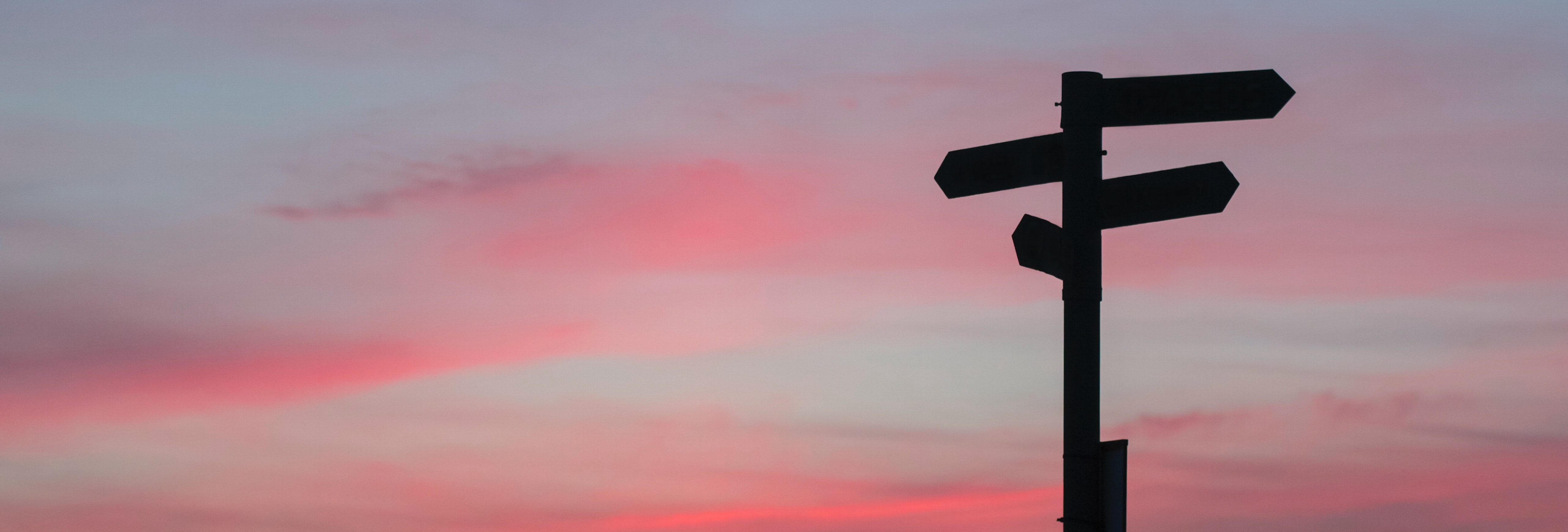 Sign posts pointing in different directions during sunrise